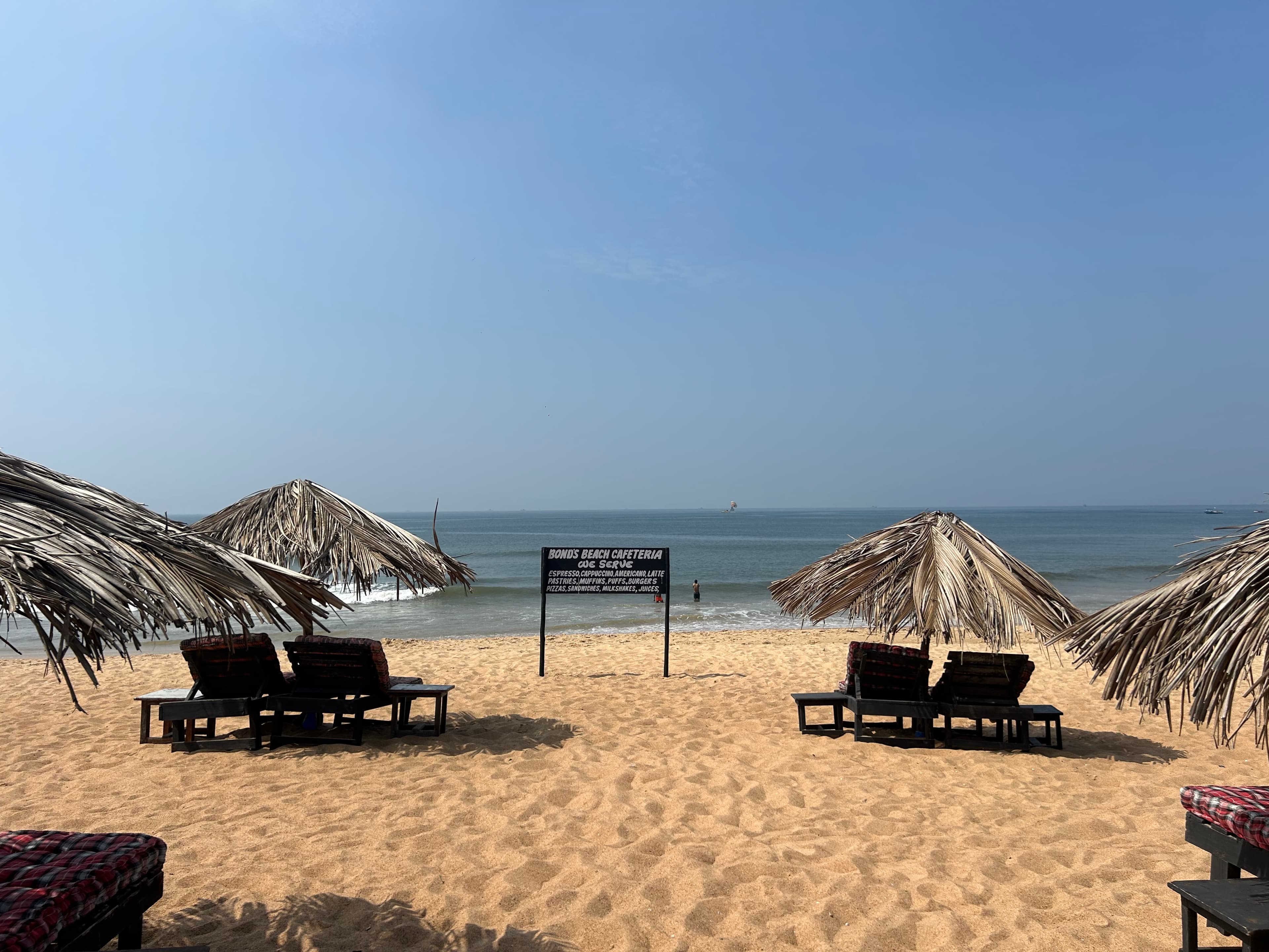 Beach loungers under thatch umbrellas facing the calm ocean