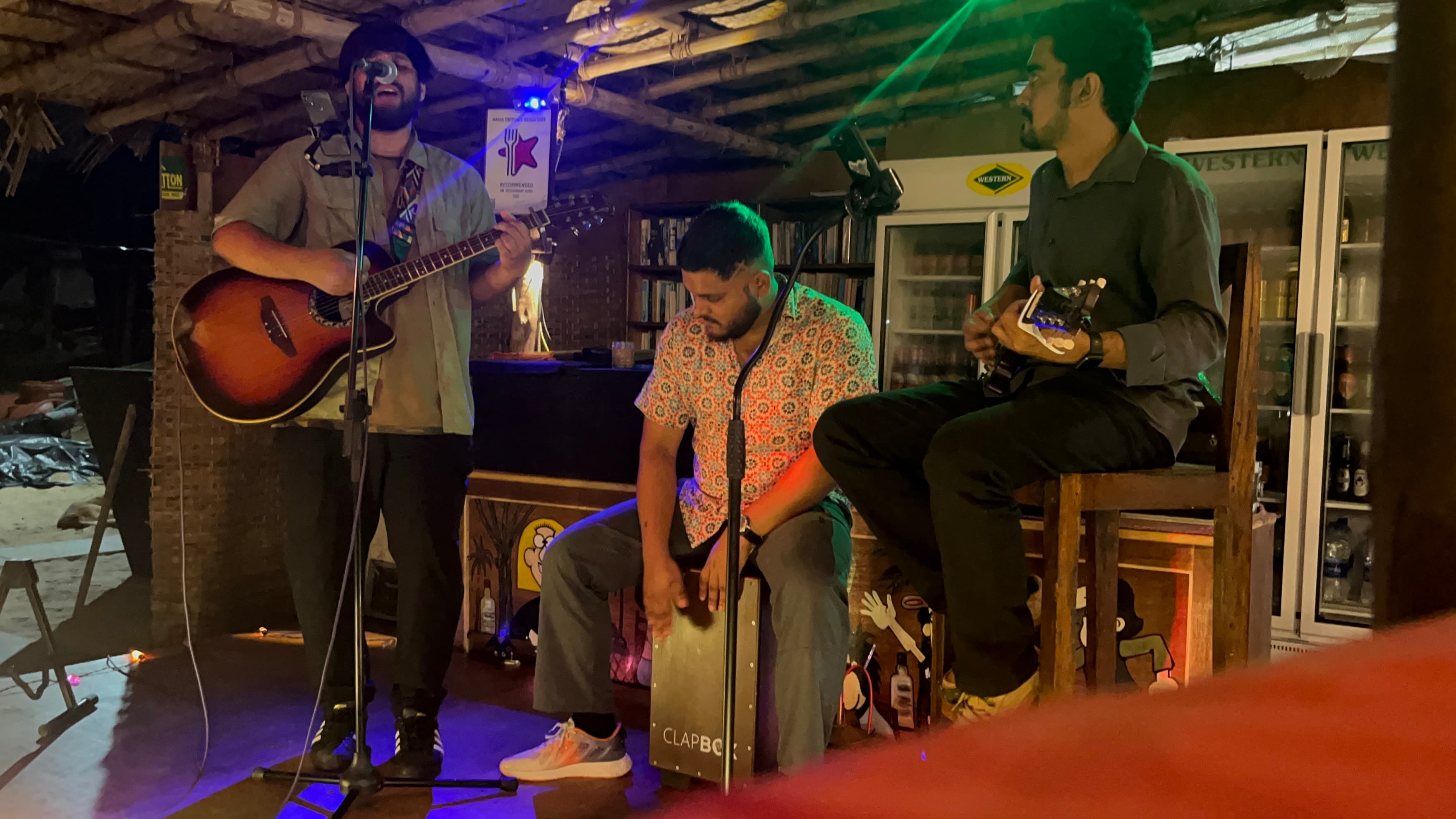Live acoustic band performing under a bamboo and thatch ceiling