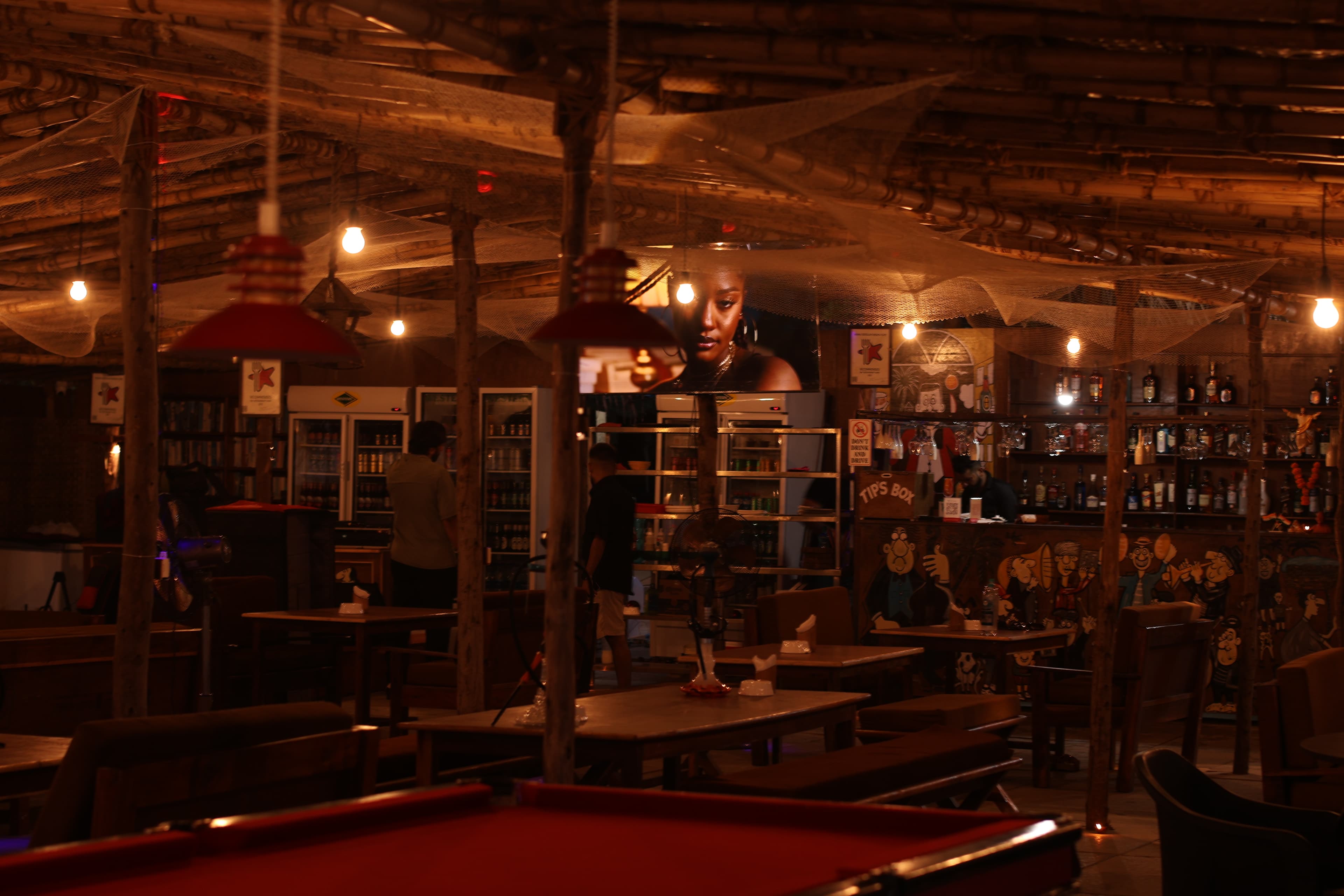 Interior bar at night with pool table, mural, and warm lighting